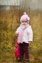 Little girl with pink umbrella in autumn park