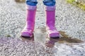 Little girl with pink wellys in the puddle