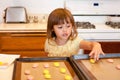 Little girl placing cookie dough on cookie sheet