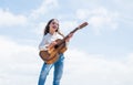Little girl play guitar she loves music. music school classes. small guitar player on sky background. country music Royalty Free Stock Photo