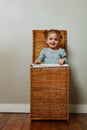 Little girl play hiding and popping out of laundry wooden box Royalty Free Stock Photo