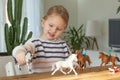 Little girl playing with animal toys on a wood table in living room Royalty Free Stock Photo