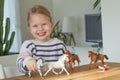 Little girl playing with animal toys on a wood table in living room Royalty Free Stock Photo