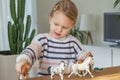 Little girl playing with animal toys on a wood table in living room Royalty Free Stock Photo