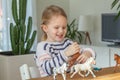 Little girl playing with animal toys on a wood table in living room Royalty Free Stock Photo