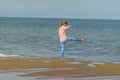 Little girl playing on a beach against the sea waves