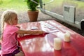 Little girl playing cards on an outdoor table at a campsite Royalty Free Stock Photo