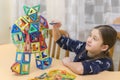 Little girl playing colorful magnet plastic blocks kit at indoor playground. girl made a toy robot. The child playing educational