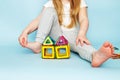 Little girl playing with colorful magnetic constructor toy on blue background. child built a house Royalty Free Stock Photo