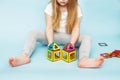 Little girl playing with colorful magnetic constructor toy on blue background. child built a house