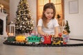 Little girl playing with colorful train toy in room decorated for Christmas Royalty Free Stock Photo