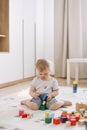 Little girl playing with colorful wooden brickes on the floor in the kids room Royalty Free Stock Photo