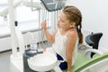 Little girl playing at the dentist. caucasian girl pours water into a plastic cup from dental equipment. Visiting dentist with