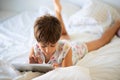 Little girl playing with digital tablet on the bed. Royalty Free Stock Photo