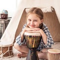 Little girl playing on djembe drums