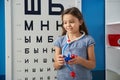 Little girl playing doctor with oculists sign at medical office.