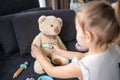 Little girl playing doctor with toys and teddy bear on the sofa in living room at home Royalty Free Stock Photo