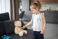 Little girl playing doctor with toys and teddy bear on the sofa in living room at home Royalty Free Stock Photo