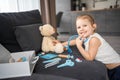 Little girl playing doctor with toys and teddy bear on the sofa in living room at home Royalty Free Stock Photo