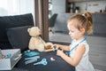 Little girl playing doctor with toys and teddy bear on the sofa in living room at home Royalty Free Stock Photo