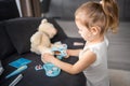 Little girl playing doctor with toys and teddy bear on the sofa in living room at home Royalty Free Stock Photo