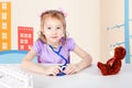 Little girl is playing doctor. She treats a teddy bear. Royalty Free Stock Photo