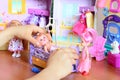 Little girl playing with dolls. Girl holding a doll in her hand. Dolls, toy furniture, clothes on a table Royalty Free Stock Photo