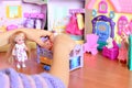 Little girl playing with dolls. Girl lays a doll down to sleep on a bed. Colorful toy set on a table Royalty Free Stock Photo
