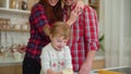 Little girl playing with dough and parents watching her