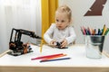 Little girl playing with electronic robot arm at home