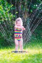 Little girl playing with garden sprinkler