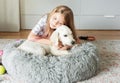 Little girl playing with a golden retriever puppy at home Royalty Free Stock Photo