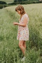 Little girl playing in green wheat field in summertime