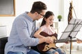 Little girl playing guitar with her teacher at music lesson Royalty Free Stock Photo