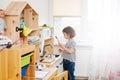 Little girl playing in her nursery room with toy child`s dishware, cooking food Royalty Free Stock Photo