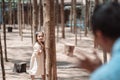 Little girl playing hiding behind tree and waving hand with family Royalty Free Stock Photo