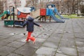 Little girl playing and jumping in rain puddle on an empty kids playground during a winter day in Bucharest, Romania Royalty Free Stock Photo