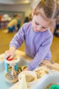Little girl playing with kinetic sand and wooden toys. Sensory development and experiences, themed activities with Royalty Free Stock Photo