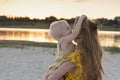 Little girl playing with moms hair. Portrait in motion mother and child on river and sunset background Royalty Free Stock Photo