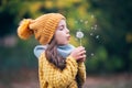 Little girl playing outdoor in autumnal park and blowing dandelion. Autumn trees in city park Royalty Free Stock Photo