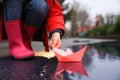 Little girl playing with paper boat near puddle outdoors, closeup Royalty Free Stock Photo