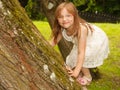 Little girl playing in park climbing to e tree.