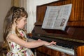 Little girl is playing the piano. A beautiful child is at a music lesson. Baby learns to play the piano Royalty Free Stock Photo
