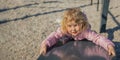 A little girl playing in the playground climbs the hill. A healthy spring or fall activity for children. The child plays