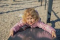 A little girl playing in the playground climbs the hill. A healthy spring or fall activity for children. The child plays