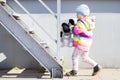 Little girl is playing with plush toys near metal staircase on bright sunny afternoon Royalty Free Stock Photo