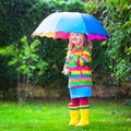 Little girl playing in the rain under colorful umbrella Royalty Free Stock Photo