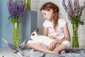 Little girl playing with real rabbit. Child and white bunny on Easter on flower background. Kids and pets play. Fun and friendship Royalty Free Stock Photo