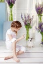 Little girl playing with real rabbit. Child and white bunny on Easter on flower background. Kids and pets play. Fun and friendship Royalty Free Stock Photo