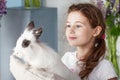 Little girl playing with real rabbit. Child and white bunny on Easter on flower background. Kids and pets play. Fun and friendship Royalty Free Stock Photo